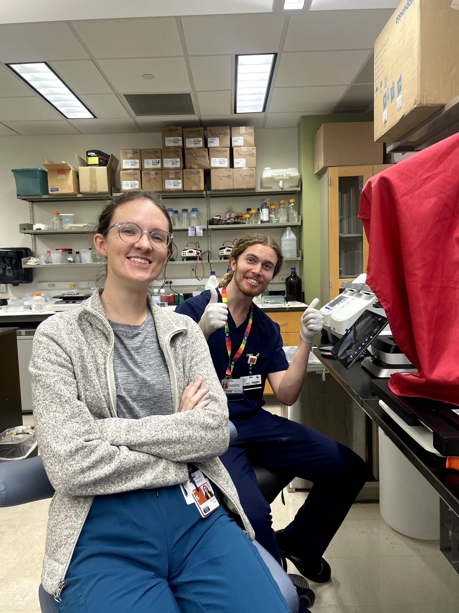 Two researchers in a lab give a thumbs up