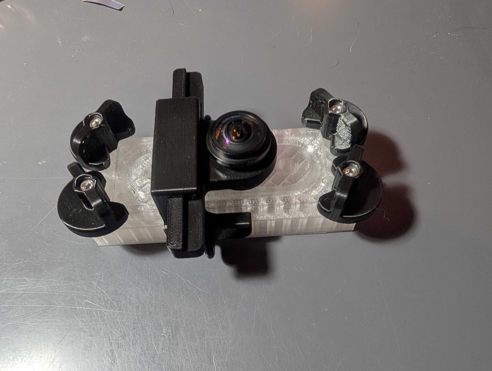 A clear 3D-printed filter device with black twist clamps and a fish-eye lens mounted on top