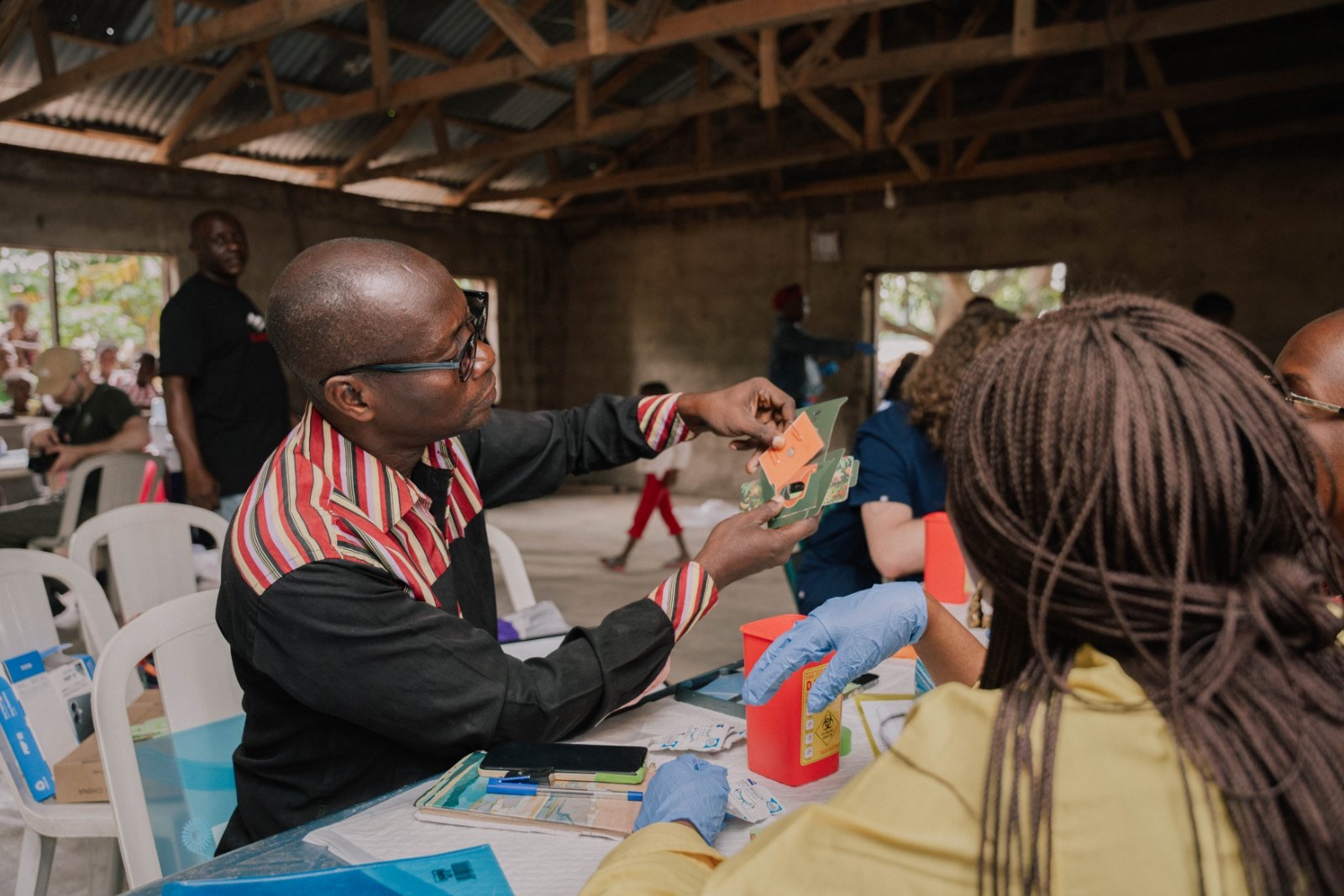 A community health worker reading a Foldscope sample with a participant during a field screening in Ogun State, Nigeria